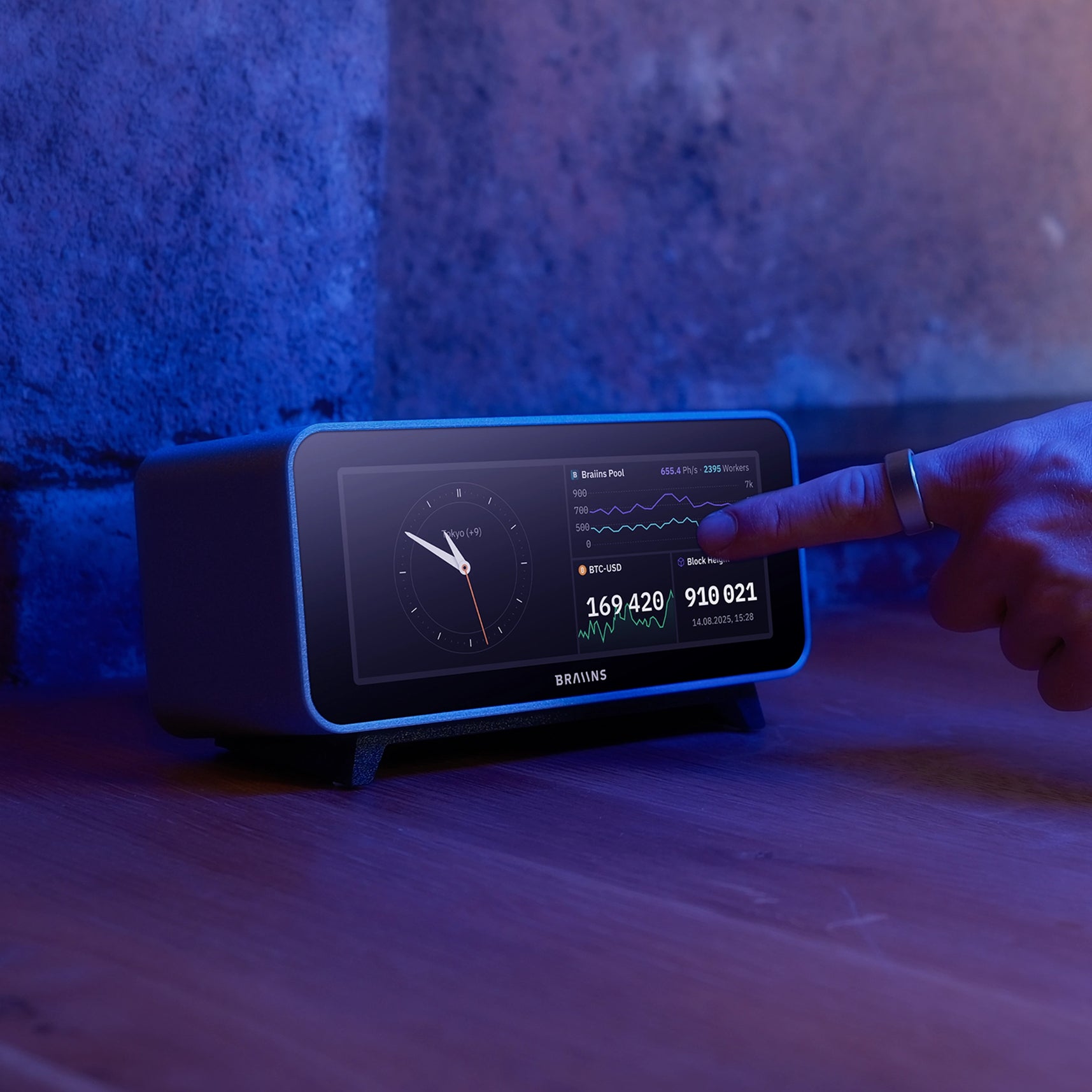 Digital clock with a person interacting with it on a wooden surface.